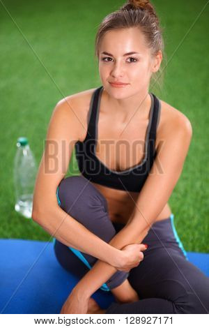 Beautiful young woman relaxing after exerscises on the grass