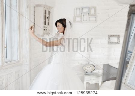 Beautiful bride making selfie by mobilephone. Side view.