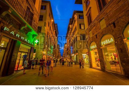 FLORENCE, ITALY - JUNE 12, 2015: Florence at night. Shops open late on summer, people visiting historical center, nice buildings with holding blue sky.