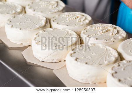 White cakes with ornament. Cakes on pieces of paper. Simple cake decoration idea. Quality cakes from local plant.