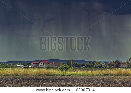 Cloudburst over a village and farmlands during spring in Transylvania region Romania.