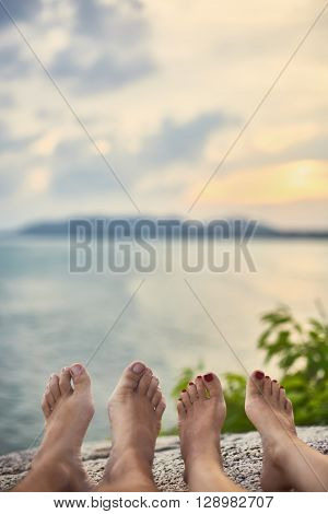 Couple's feet relax on top of mountain with sea view. vacation concept