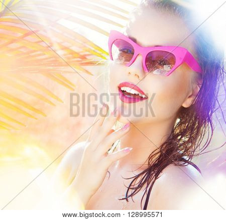 Colorful summer portrait of happy young attractive woman wearing wet sunglasses. wet hair beauty and fashion concept. natural bokeh and light effect