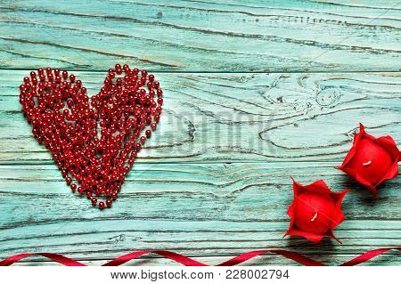 Red Heart Piled Of Beads On A Wooden Turquoise Background. The Concept Of Valentine's Day.