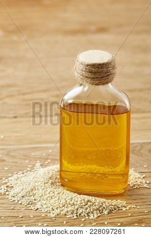 Peeled Sesame Seeds With Oil In A Small Transparent Glass Bottle Over Rustic Wooden Background, Shal