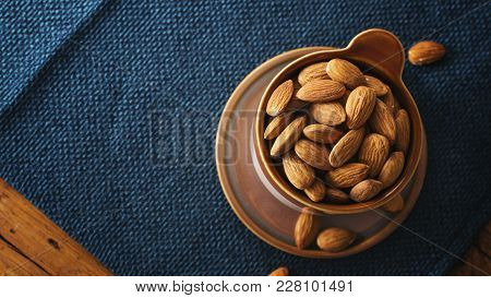Almond In Ceramic Cup On Blue Nupkin, Copy Space.