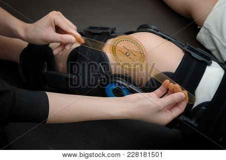 Physiotherapist Measuring Range Of Motion On Patients' Knee With Goniometer