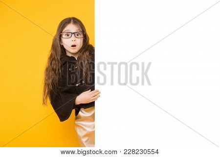 Portrait Of Cute Long-haired Surprised Little Girl In Jacket And Eyeglassesisolated On Yellow Backgr