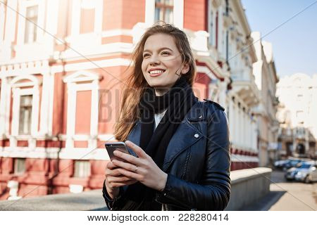 Excellent Day For Adventures. City Portrait Of Attractive European Girl Walking In Street, Holding S