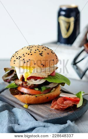A Large Burger With A Cutlet, Vegetables, Egg And A Fresh Roll. Sandwich For Breakfast. Fast Food.