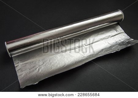 The Aluminum Foil Used For Cooking In The Kitchen Stands On The Black Floor.