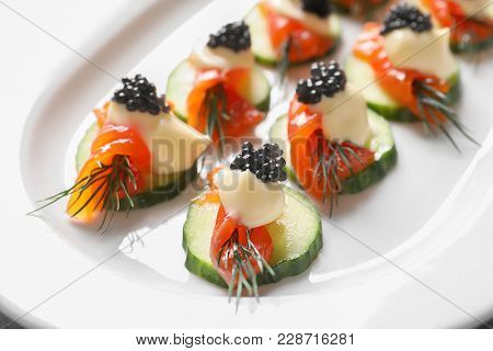 Delicious canapes with black caviar on plate, closeup