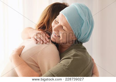 Woman hugging her mother with cancer indoors