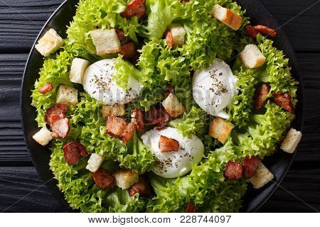 French Salad Lyonnaise With Lettuce, Crispy Bacon, Croutons And Poached Eggs Close-up On A Plate. Ho