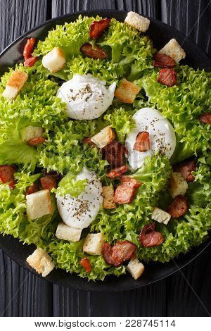 French Salad Lyonnaise With Lettuce, Crispy Bacon, Croutons And Poached Eggs Close-up On A Plate. Ve