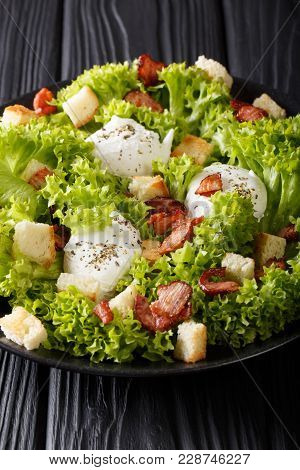 Gourmet Salad Lyonnaise With Lettuce, Crispy Bacon, Croutons And Poached Eggs Close-up On A Plate. V