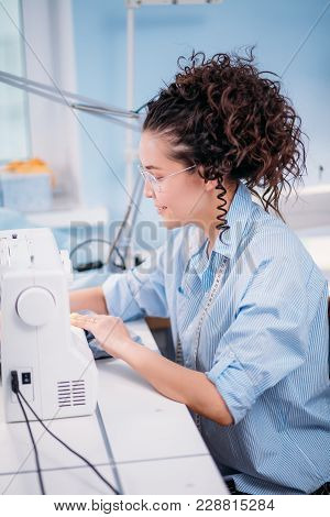 Sede View Photo Of Hardworking Seamstess Making Clothers With Sewing Machine. Creating New Style. Fa