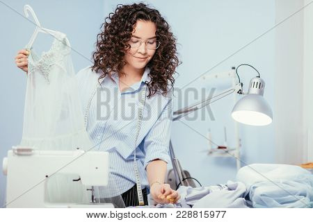 Woman Giving Finishing Touch Of Making Dress At Design Studio. Small Business.
