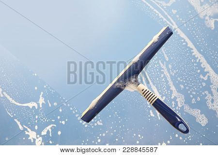 Squeegee Cleaning A Soapy Window, Spring Cleaning Concept, Blue Sky With Copy Space