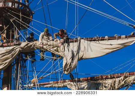Sailors Work With Sails At A Height On A Traditional Sailboat In The Sea