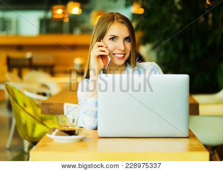 Image of happy woman using laptop and smartphone in cafe. Lifest