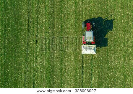 Agricultural Tractor Is Fertilizing Wheat Crop Field With Npk Fertilizers, Aerial View From Drone Po