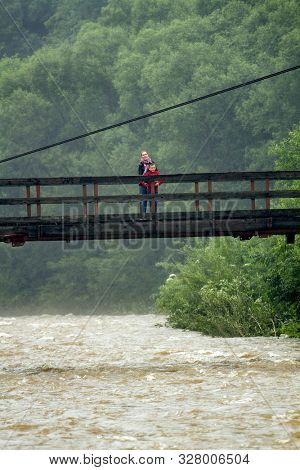 Mother and son on the bridge. Happy woman and little boy walking outdoors in the old green forest
