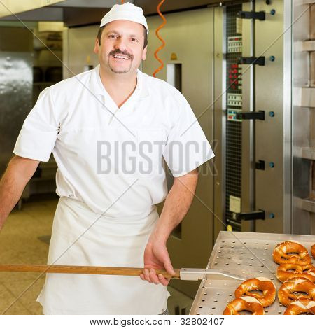padeiro em pé na sua padaria na parte da manhã e assa pão ou pãezinhos