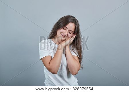 Young Caucasian Girl With White T-shirt Making Sleep Gesture In Dorable Expression. On A Grey Backgr