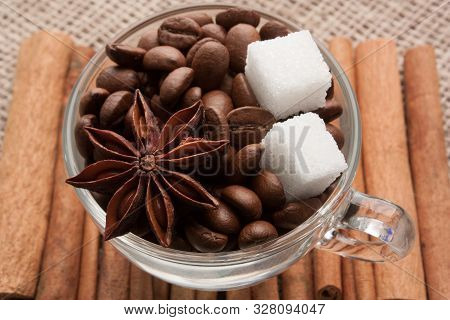 Coffee Beans In Glass Cup With Sugar And Anise Star On Cinnamon Sticks, Which Lie On Sackcloth.