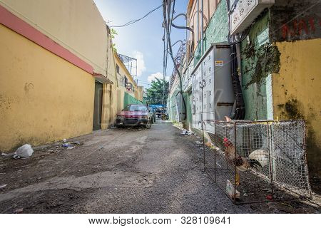 Santo Domingo, Dominican Republic; April 13, 2014: Alley To Park Cars With Garbage And A Chicken Loc