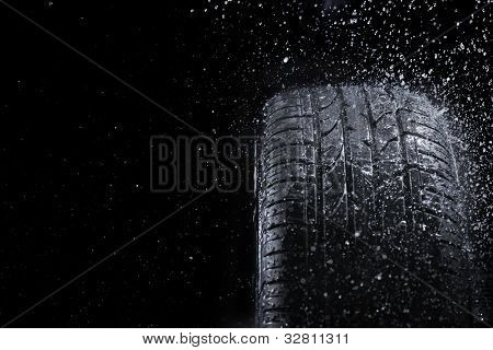 Nuevo neumático de coche en lluvia.