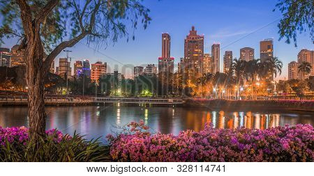 Lake In City Park Under Skyscrapers At Night. Benjakiti Park In Bangkok, Thailand