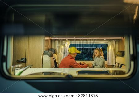 Family Rv Camper Trip. Caucasian Father And Daughter Playing Inside Motorhome. Seating In Dinette Se
