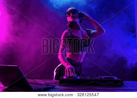 Young Sexy Woman Dj In Bra And Sunglasses Playing Music. Headphones And Dj Mixer On Table. Colorful 