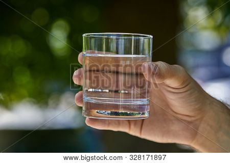 Partial View Of Man Holding Glass With Clear Fresh Water Outdoor