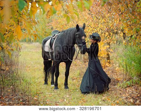 Horsewoman Girl In A Black Dress Leads A Black Horse