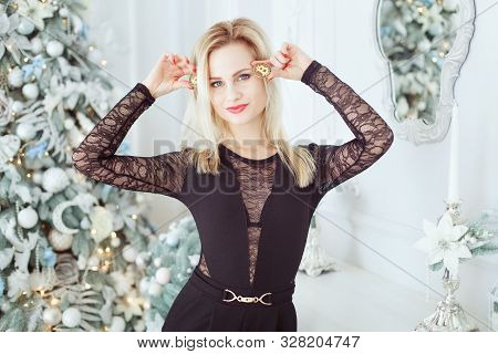 Young Beautiful Blonde Holds Bitcoin Coins In Her Hands. She Is Standing Near The Christmas Tree.