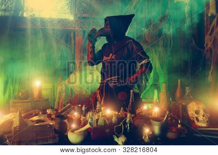 The plague doctor is working at his desk, inventing a cure for bubonic plague. The atmosphere of mysticism. Historical reenactment. Halloween. 