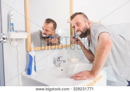 Man Brushing His Teeth In Bathroom