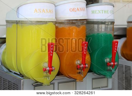 Dispenser With Many Ice With Syrup With Text In French That Means Pineapple, Orange And Mint