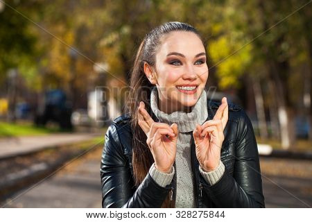 Body language and emotions concept. Young beautiful satisfied woman beggs God to help her, keeps fingers crossed, wishes good luck