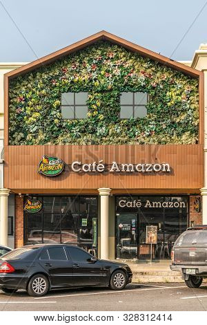 Chachoengsao, Thailand - March 17, 2019: Brown Facade With Green Foliage And Flowers Labeled Café Am