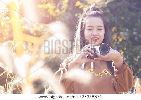 Portrait Of Beautiful Asian Girl Are Taking Photo By Campact Camera In The Garden With Sunrise.