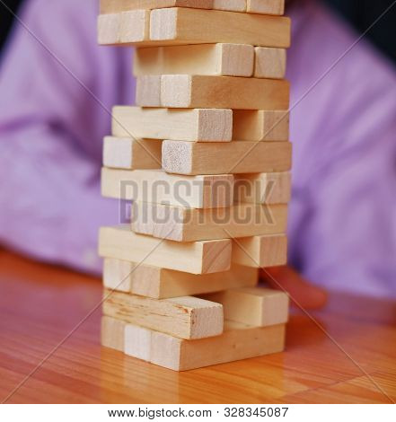 Stacks Of Block Wood Game On A Wooden Table With Player In The Background.