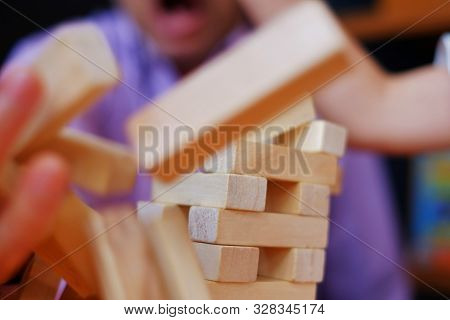 A Stacked Wooden Block Tower Falling Over With Pieces Flying Around.