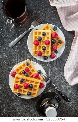 Waffles with blueberries, raspberries, maple sirup and tea cup. Top view.