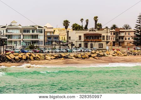 Sea Waves, Coastline Cars And Buildings On The Street Of Swakopmund German Colonial Town, Namibia