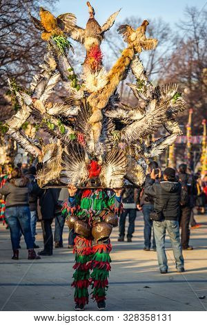 Mummers perform rituals to scare evil spirits at Surva festival at Pernik in Bulgaria. The people with the masks are called Kuker (kukeri). Wood mask with feathers and chickens.