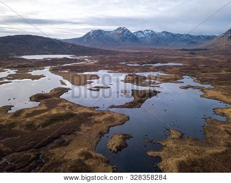 Scottish Winter Wetlands With Brown Grass Over Looking Black Mount Mountain Range On A Cloudy Day In